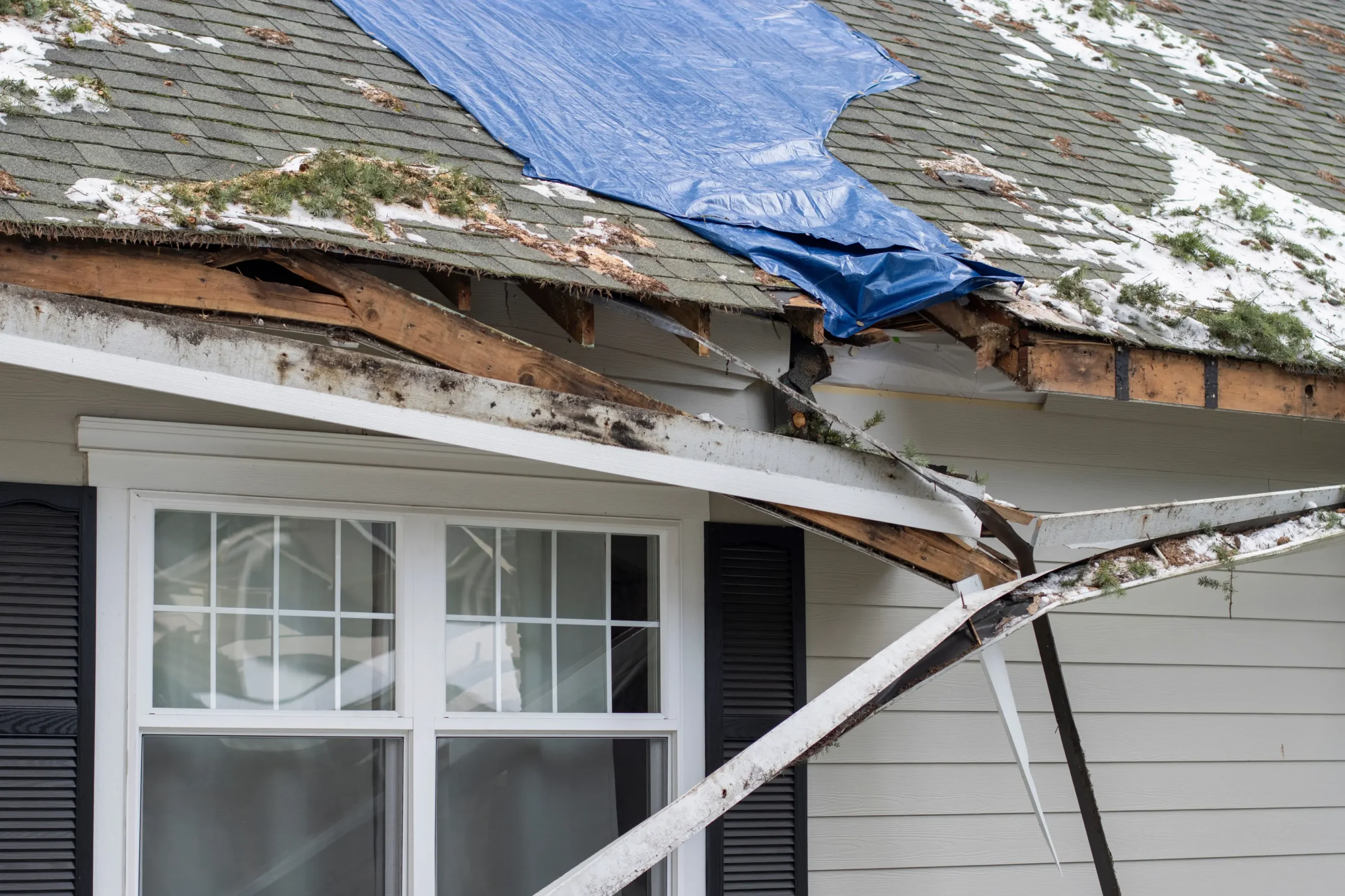 Storm-damaged residential roof awaiting repair by WOW Roofing & Gutters after severe weather.
